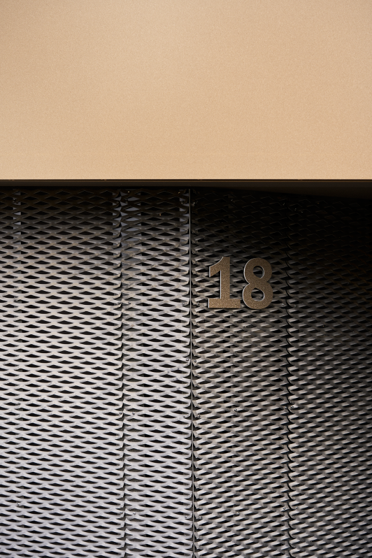 Detailansicht einer modernen Fassade aus perforierten Metalllamellen mit der Hausnummer - geplant und umgesetzt von arc+ Freudenstadt