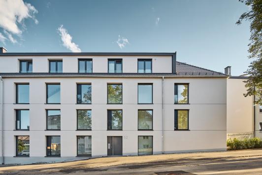 Straßenansicht einer Wohnanlage in Freudenstadt mit heller Putzfassade und regelmäßig angeordneten Fenstern. geplant von arc+ Freudenstadt