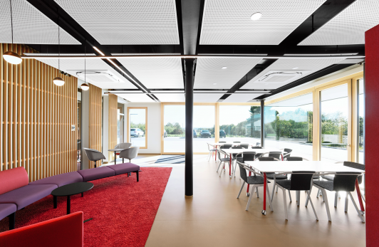 Aufenthalts- und Essbereich im Verwaltungsbau Gläser in Horb mit Tischen, Stühlen, Lounge-Sofa und roten Farbakzenten geplant und ausgeführt Architektur arcplus