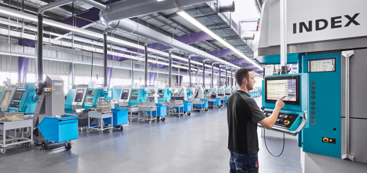 Produktionshalle von ›Grohe Technology‹ mit Reihen moderner Fertigungsmaschinen und digital gesteuerter Bedieneinheit, gestaltet im Rahmen des architektonischen Konzepts von arcplus Architekten.
