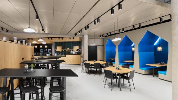 Aufenthalts- und Gastronomiebereich im HF Mixing Neubau mit offenen Sitzgruppen, Hochtischen und akustisch geschützten Nischen – geplant und umgesetzt von arcplus