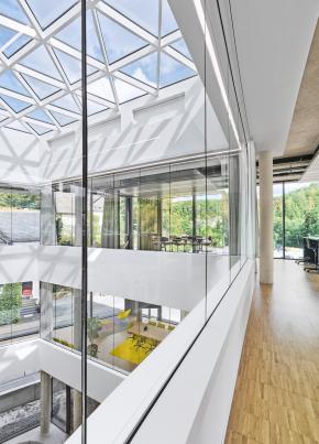Offenes Atrium mit großflächigem Glasdach, verglasten Besprechungsräumen, umlaufenden Galerien und lichtdurchfluteten Arbeitsbereichen im Verwaltungsneubau der HF Mixing Group in Freudenberg. Das moderne Raumkonzept verbindet die Geschosse miteinander und schafft eine offene Arbeitswelt für einen weltweit führenden Hersteller von Mischanlagen und Prozesslösungen für die Reifenindustrie, die technische Gummiwarenindustrie sowie Spezialanwendungen der Elastomerverarbeitung. Bauherr: HF Mixing Group. Geplant und umgesetzt von arc+ GmbH Freudenstadt.