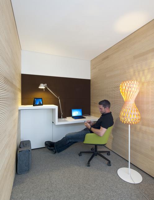 Rückzugsraum im Hansgrohe Office Schiltach mit integrierter Arbeitsnische, Holzverkleidung und wohnlicher Beleuchtung – gestaltet von arcplus aus Freudenstadt