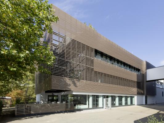 Sanierte Fassade des Hansgrohe Werks Aue in Schiltach mit horizontaler Holzlamellenstruktur und nachhaltigem Fassadenkonzept – geplant von arc+ Freudenstadt