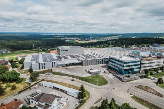 „Luftaufnahme des erweiterten Homag-Standorts in Schopfloch mit moderner Logistikhalle, Verwaltungsgebäude und großflächiger Photovoltaikanlage geplant und umgesetzt von arc+